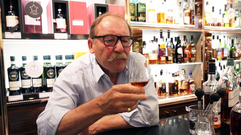 Charles MacLean examining the appearance of a glass of whiskey
